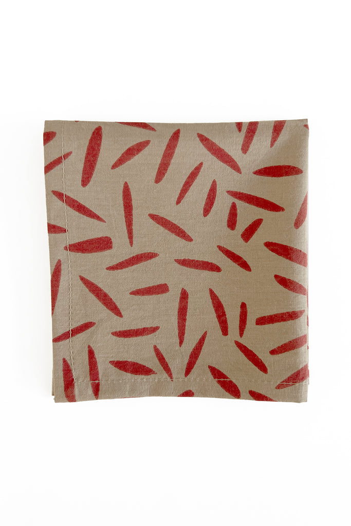 A set of 4 red and beige cotton cocktail napkins with red leaves on them by See Design.