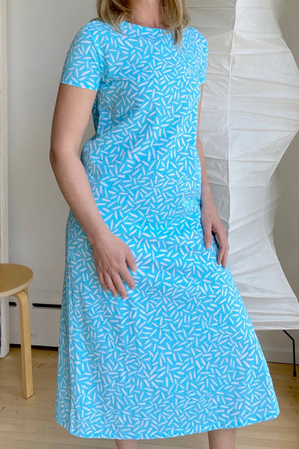 A woman is standing in a comfortable, longer See Design Knit Dress Full Length.