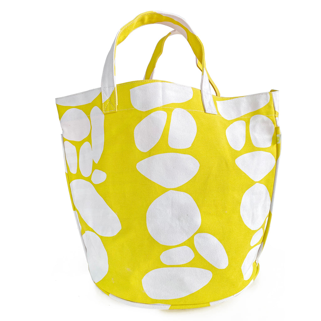 A yellow See Design Circle Tote with white abstract patterns on a white background.