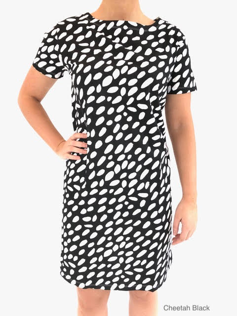 A woman wearing a comfortable and versatile See Design black and white polka dot knit dress.