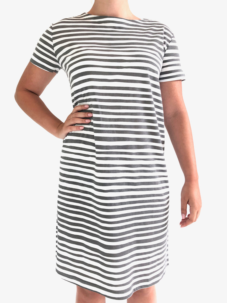 A woman wearing a comfortable See Design black and white striped short sleeve knit dress.