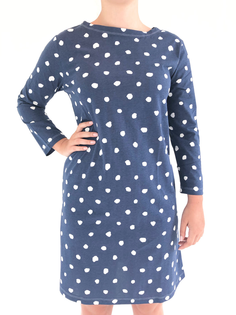 A woman wearing a versatile See Design blue and white polka dot 3/4 sleeve knit dress.