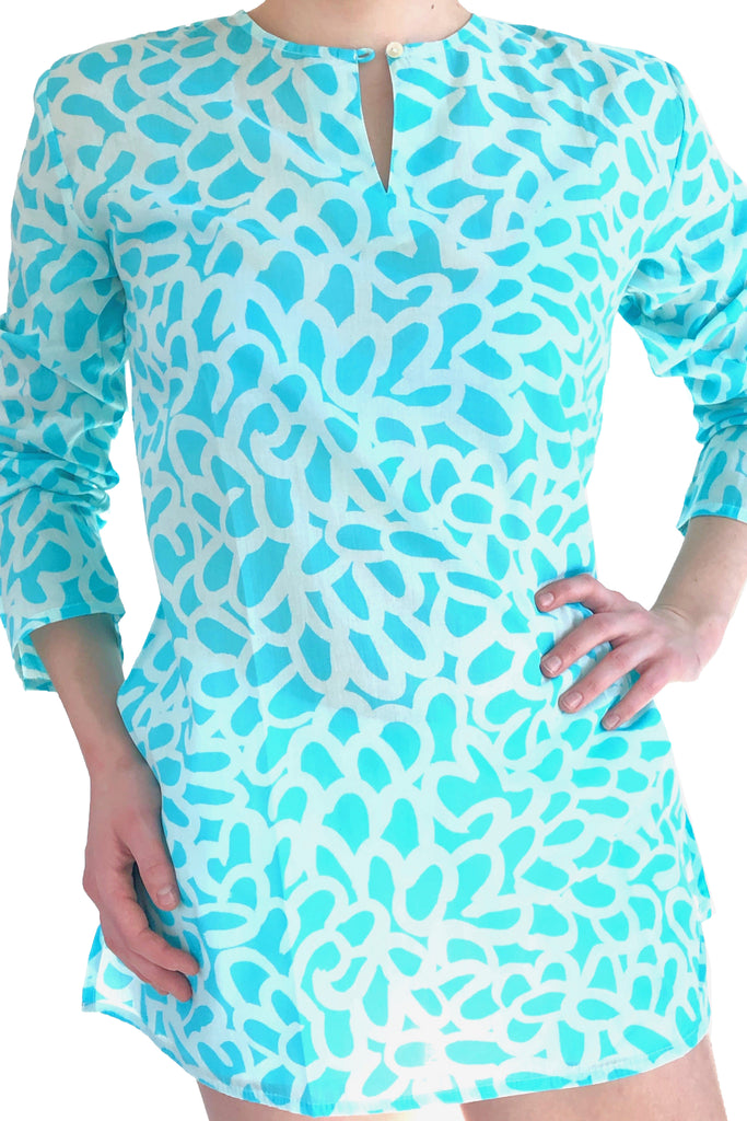 A woman is posing in a versatile and lightweight See Design turquoise and white print tunic made of cotton voile.