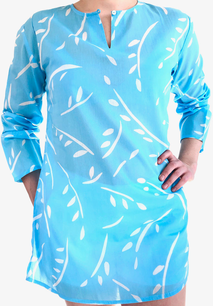 A woman wearing a lightweight blue tunic with white leaves on it made of cotton voile from See Design.