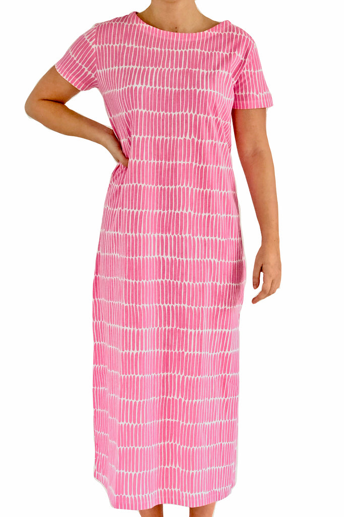 A woman wearing a comfortable See Design pink and white striped Knit Dress Full Length.