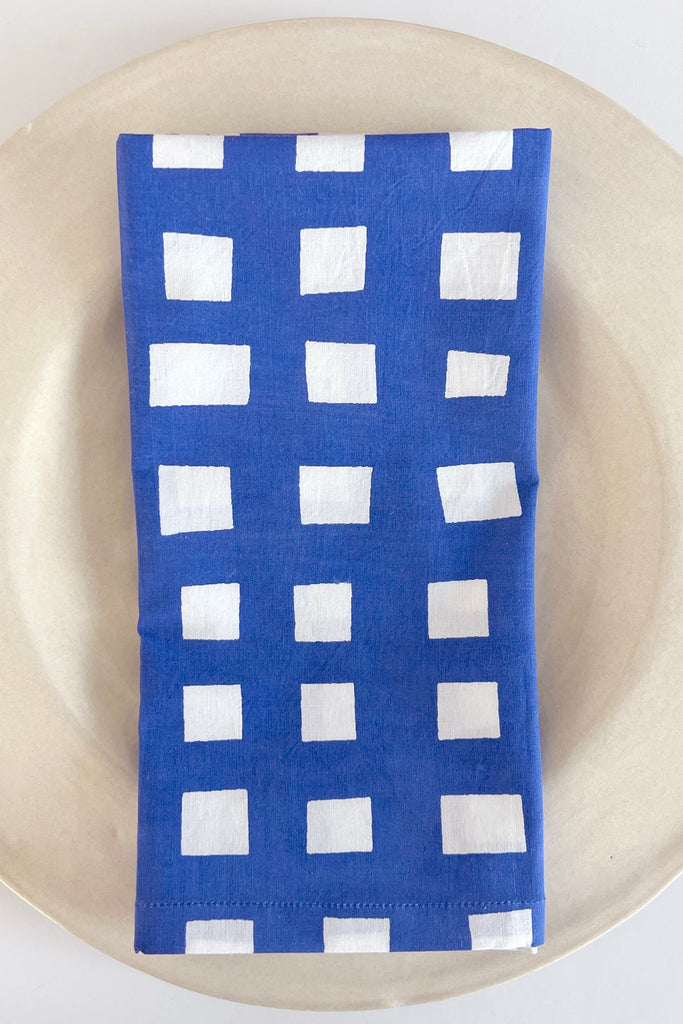 A vibrant blue and white cotton Napkins (Set of 4) on a plate, brand See Design.