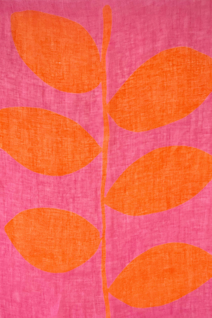 A pink and orange See Design linen scarf with colorful leaf patterns, adding a modern design element to any outfit.