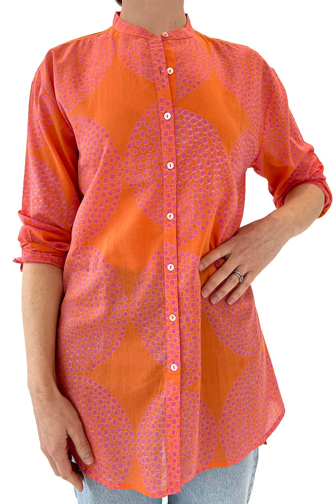 A fashionable woman wearing a vibrant orange and pink Long Shirt by See Design that exudes both comfort and style.
