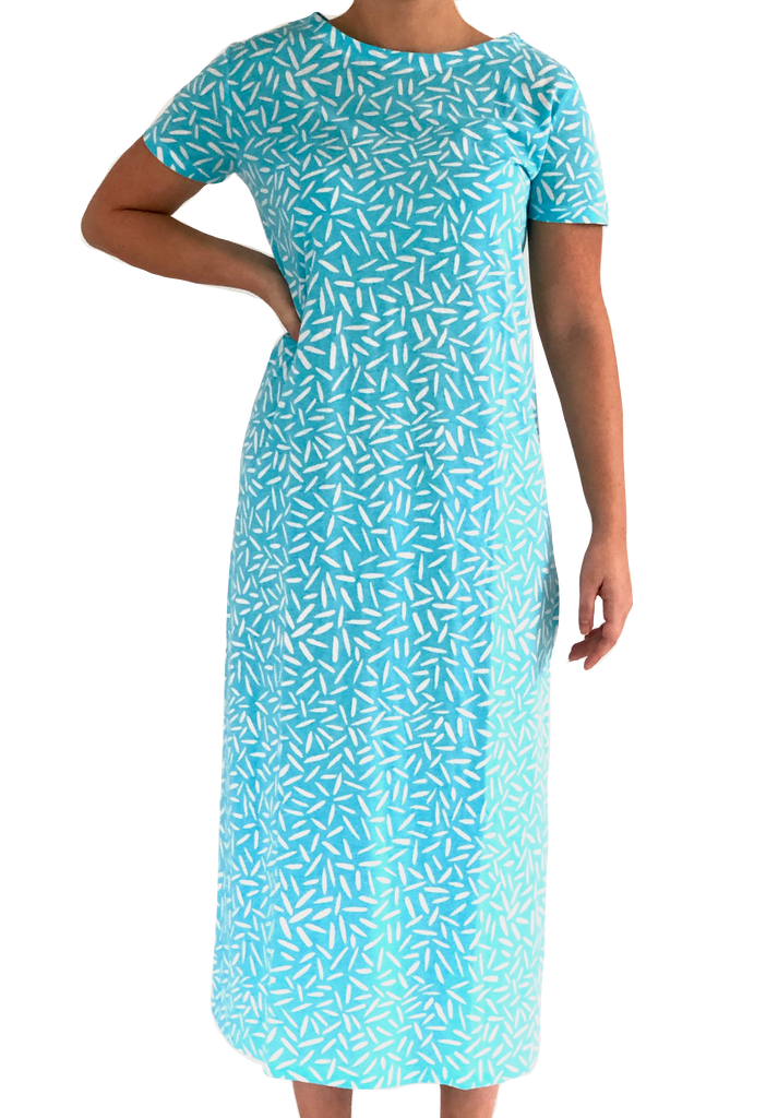 A woman wearing a comfortable See Design blue and white full-length knit dress with a boat neck collar.