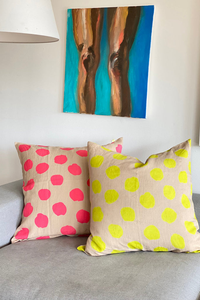 Two colorful dotted Linen 26" Pillow Covers with zipper closure on a grey sofa, with a vibrant abstract painting of human legs hanging above. (See Design)