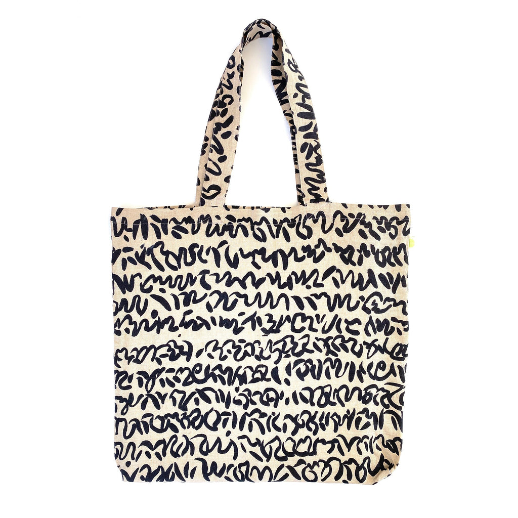 A sturdy Linen Everyday Tote Bag from See Design with black and white writing, perfect for shopping.