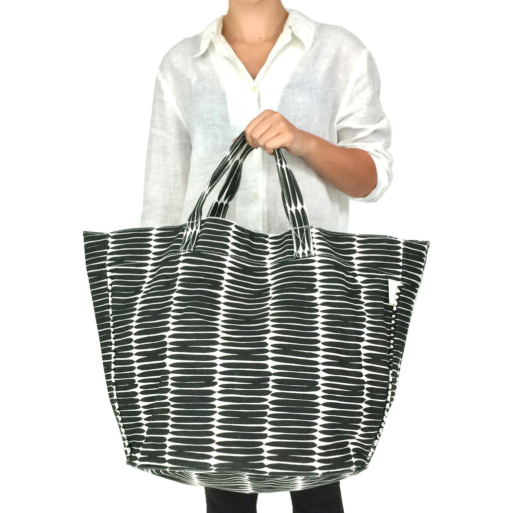 A woman holding a sturdy cotton canvas Circle Tote bag by See Design.