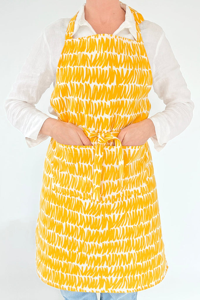 A woman wearing a See Design hand-painted apron.