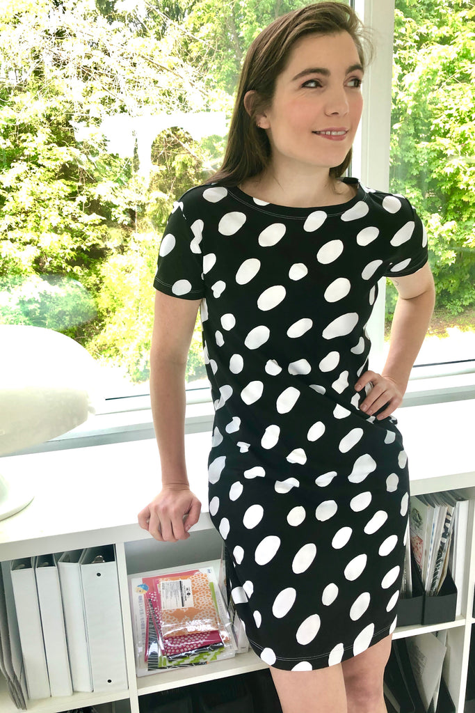 A comfortable young woman in a versatile See Design black and white polka dot knit dress short sleeve.