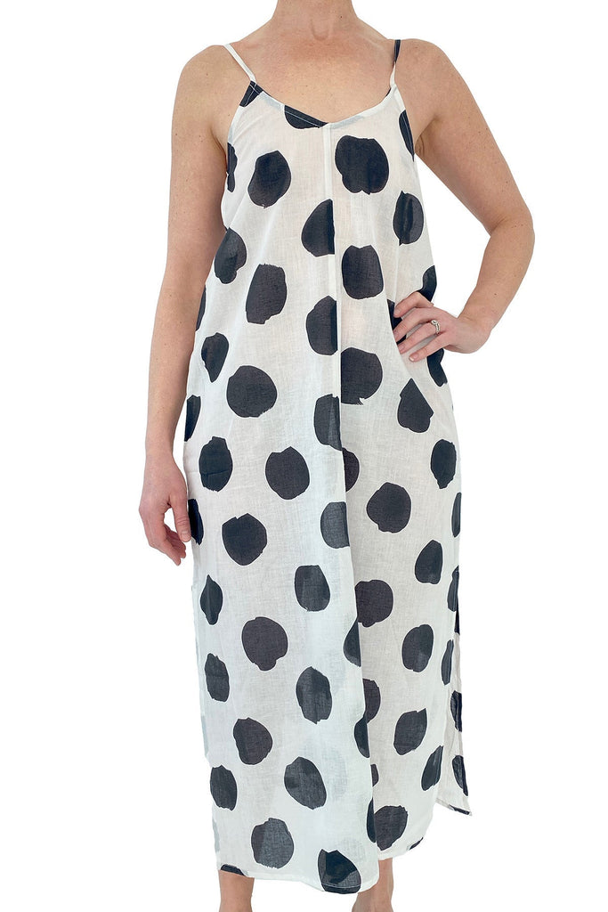 A woman wearing a lightweight black and white polka dot See Design slip dress.