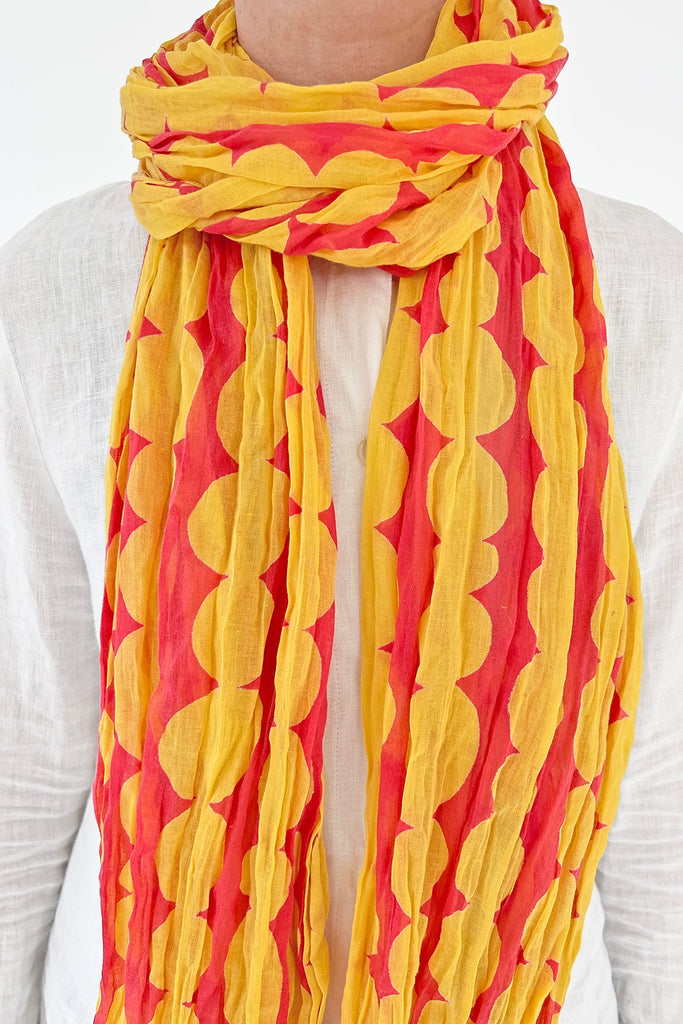 A woman wearing a See Design lightweight yellow and red cotton scarf.