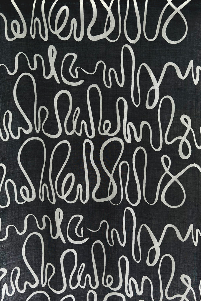 A black and white See Design wool scarf with writing on wool fabric.
