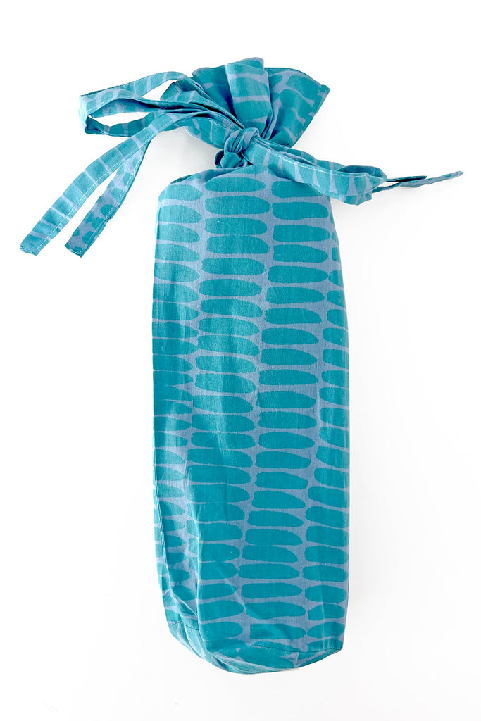 A fashionable teal bag with a See Design sarong tied around it.