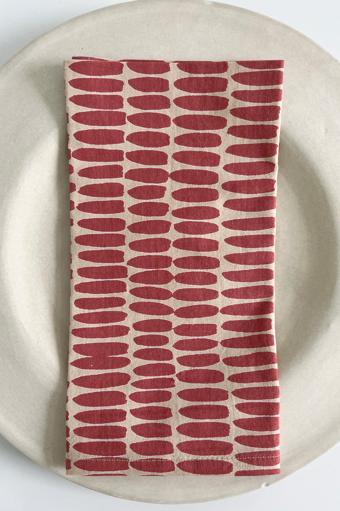 A red cotton Napkins (Set of 4) on a white plate. Brand name: See Design.