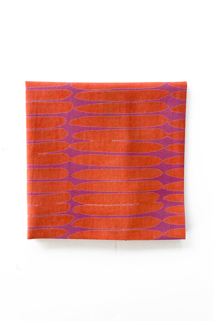 The set of 4 folded Cocktail Napkins by See Design, featuring an orange and purple patterned fabric with elongated shapes on a white background, adds a vibrant touch to any setting.