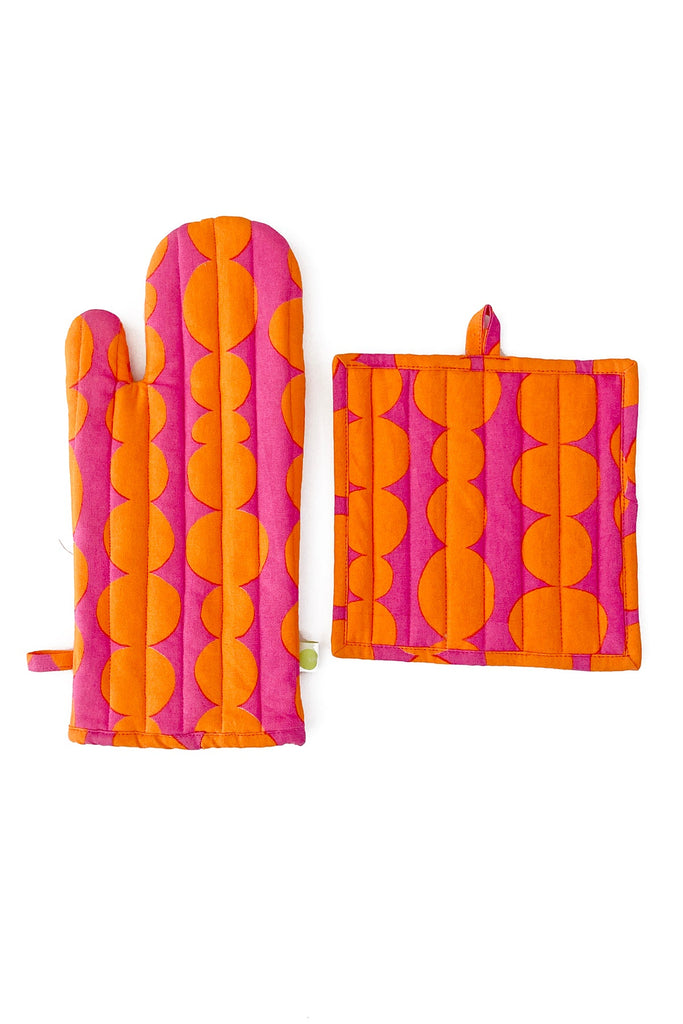 The See Design Oven Mitt & Potholder Set boasts a vibrant pink and orange geometric pattern, made from 100% cotton, elegantly displayed side by side on a white background.