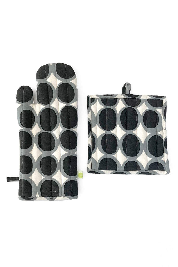The See Design Oven Mitt & Potholder Set is made from 100% cotton and showcases a chic black and gray circular pattern on a white background.