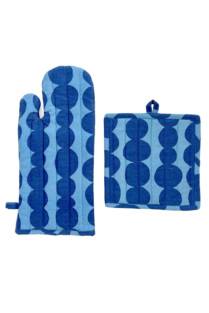The Oven Mitt & Potholder Set from See Design features a blue oven mitt and a matching potholder, both adorned with dark blue circular patterns, placed on a white background. Crafted from high-quality cotton fabric, they add a touch of elegance to any kitchen.