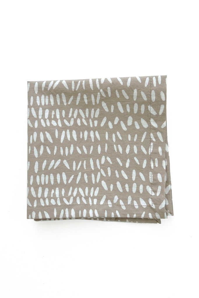 A set of four folded Cocktail Napkins by See Design, featuring a scattered white dot pattern on brown fabric, is displayed against a plain white background.