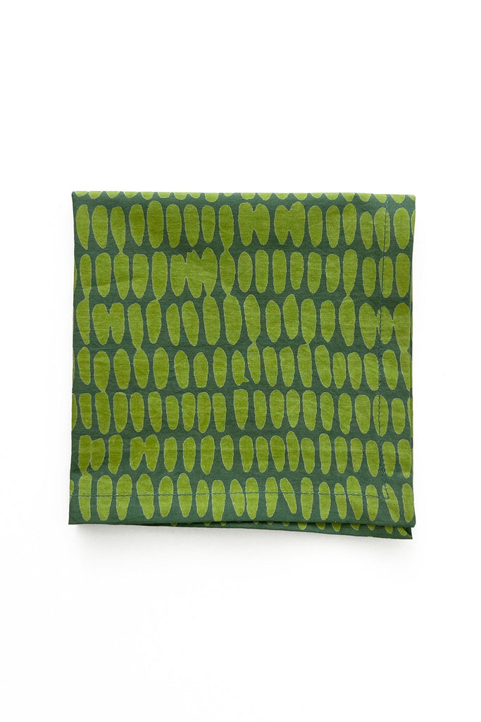 A set of four See Design Cocktail Napkins featuring a hand-painted, lime green oval pattern on green fabric, neatly folded against a plain white background.