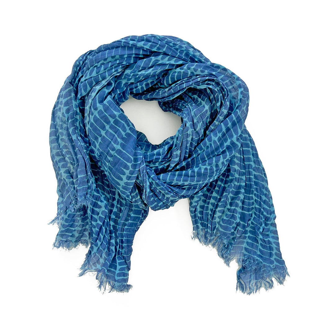 The Cotton Scarf by See Design, crafted from soft lightweight cotton and featuring fringed edges, is artfully arranged in a circular shape on a white background.