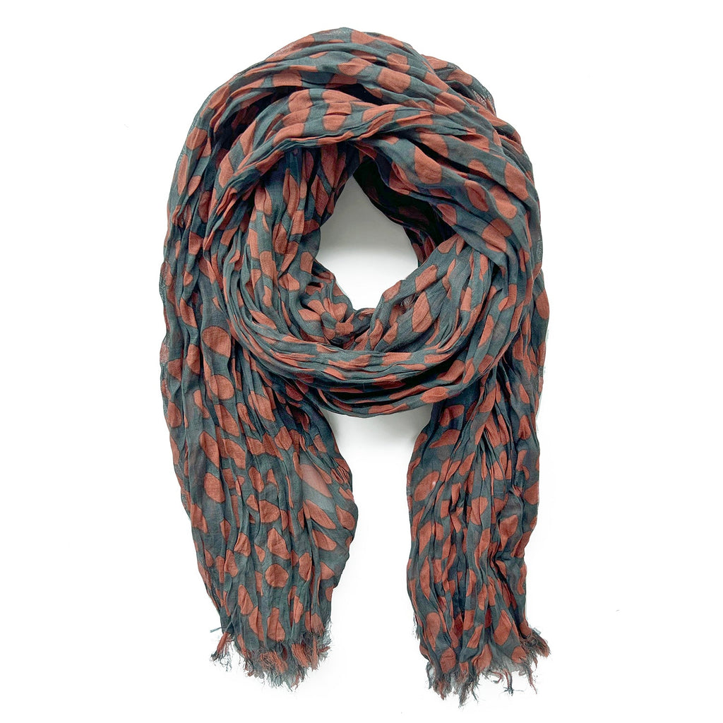 A crumpled, soft, lightweight Cotton Scarf by See Design featuring a teal and rust polka dot pattern, shown against a white background.