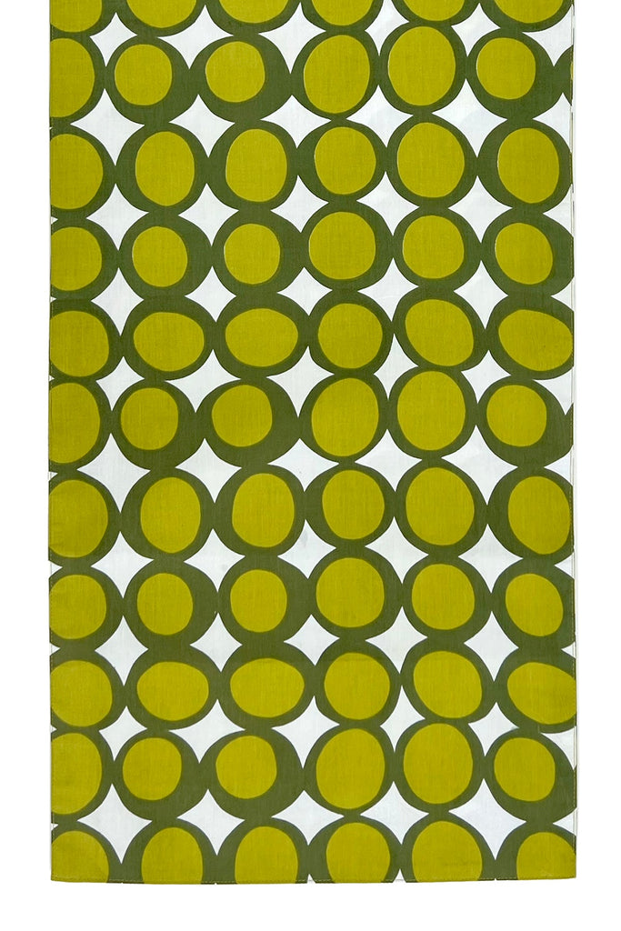 The See Design Table Runner features cotton fabric with large green and small yellow-green circles on white—ideal for adding a modern, vibrant touch to your table setting.