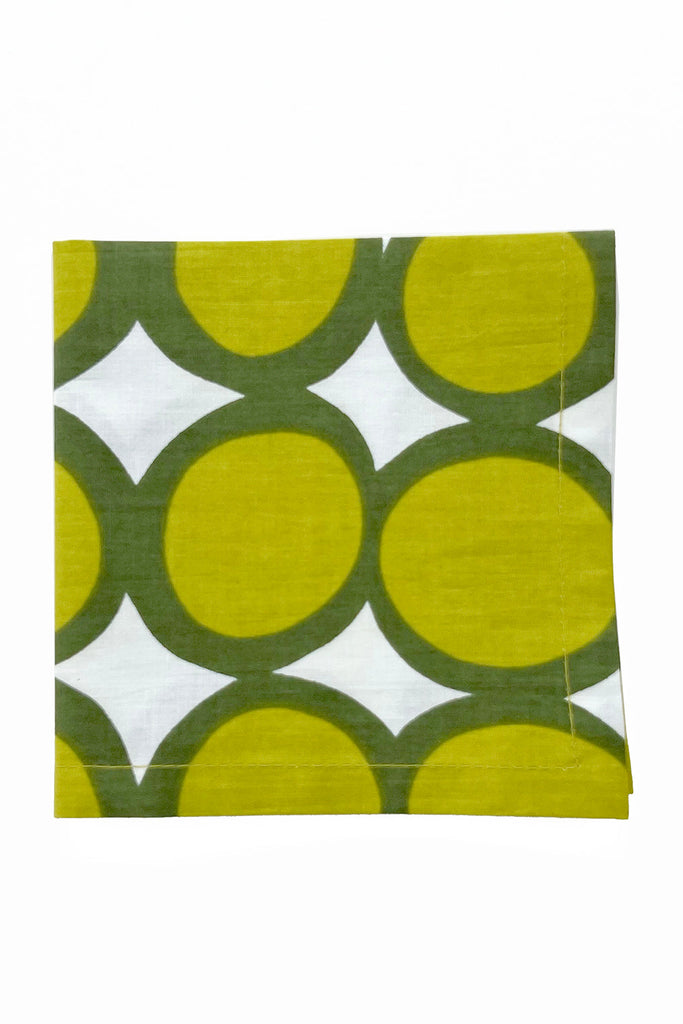 See Design Cocktail Napkins (Set of 4) feature a bold green and white geometric circle pattern, perfect for adding a pop of color to your table setting. Shown folded on a plain white background.