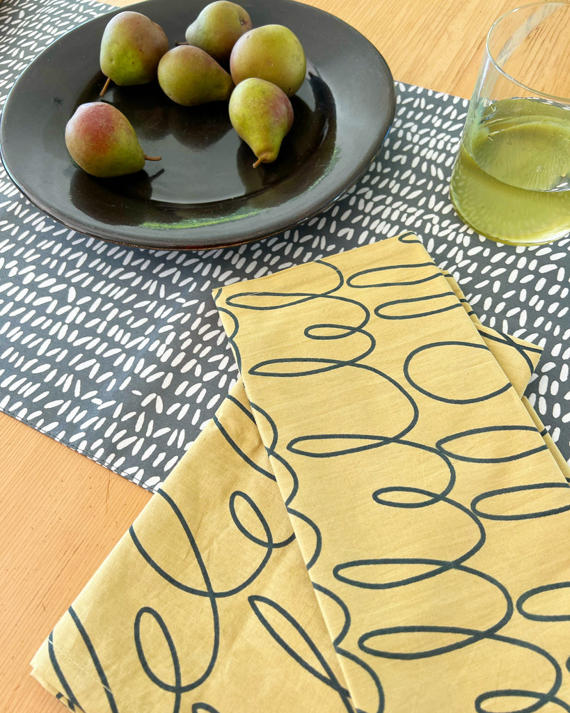 A See Design table runner and a glass of wine on a table.