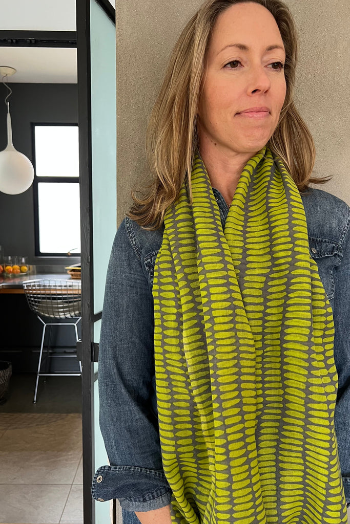 Woman wearing a green and gray patterned scarf in an indoor setting