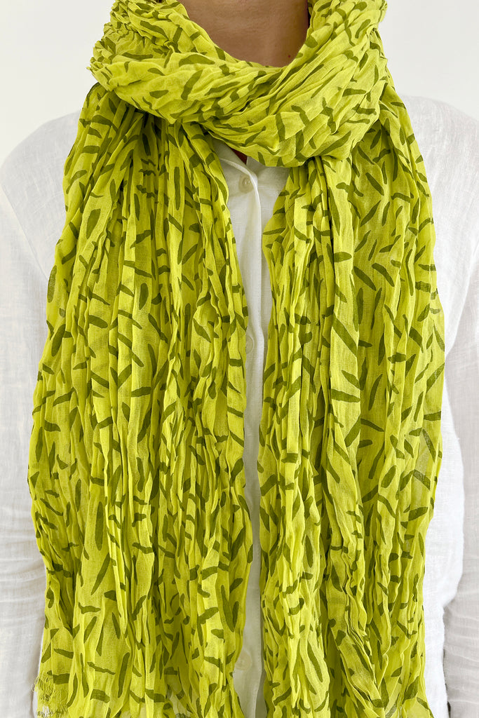 A woman wearing a lightweight See Design lime green cotton scarf.