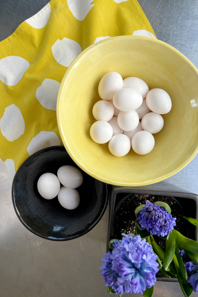 Tea towels (Set of 2) by See Design in a yellow bowl on a table next to a kitchen setting.