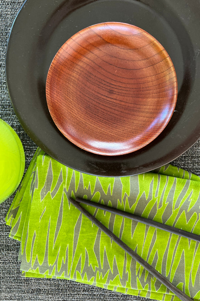 A plate with colorful table linens and chopsticks.