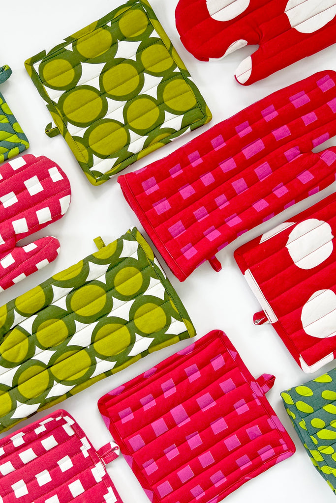 See Design Oven Mitt & Potholder Sets in green and red, featuring geometric patterns, are arranged on a white background.