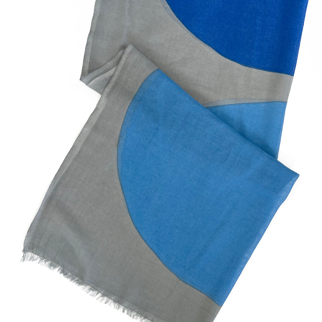 A lightweight Wool Scarf by See Design featuring geometric blue and gray color blocks and frayed edges—perfect as a shawl for any season.