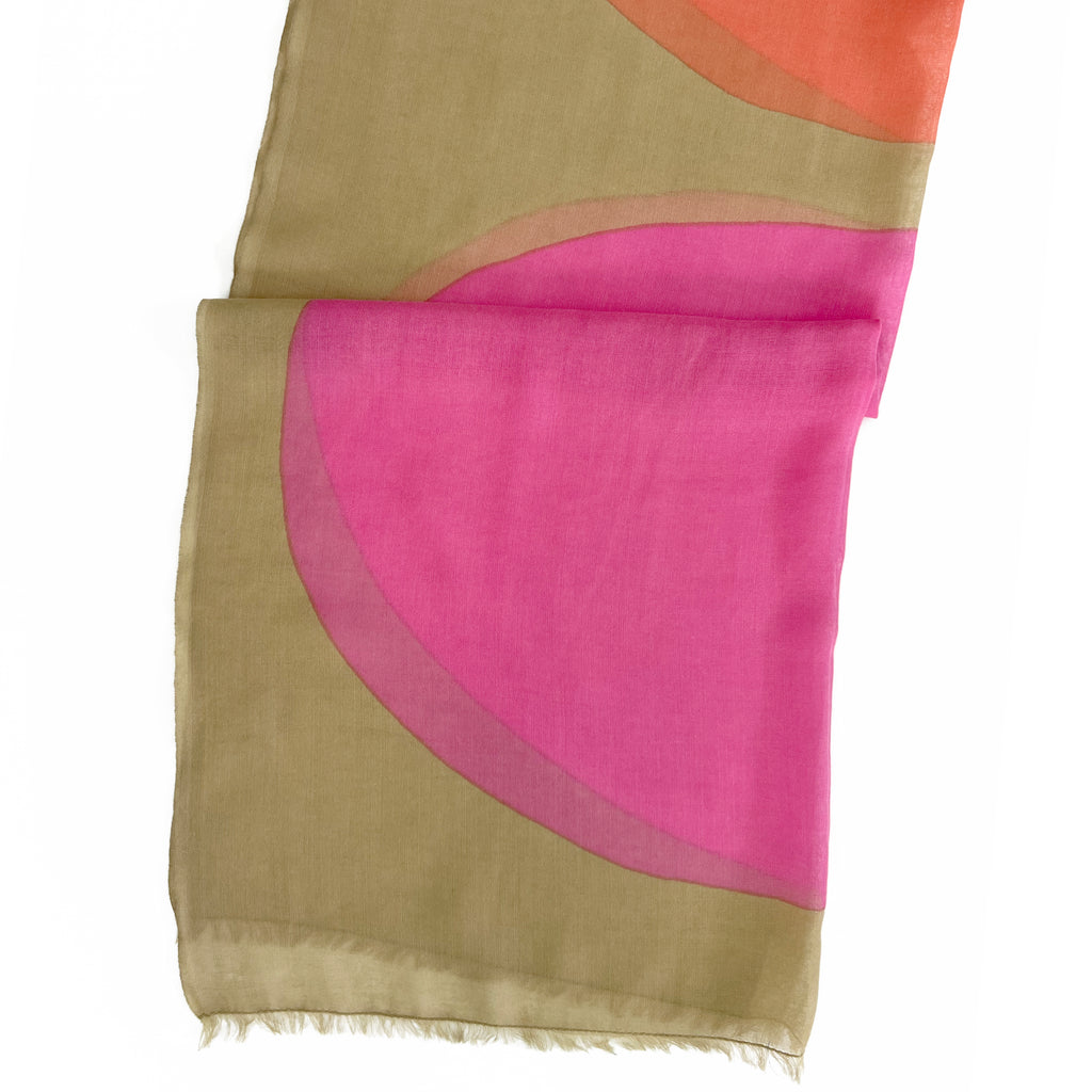 The See Design Wool Scarf features an olive green base with overlapping pink and orange semicircles and frayed edges—ideal as a lightweight shawl.