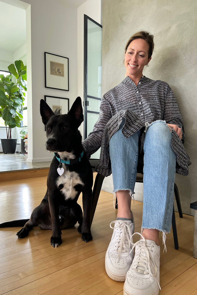 A woman sitting comfortably on a chair with her dog in a See Design stylish shirt dress.