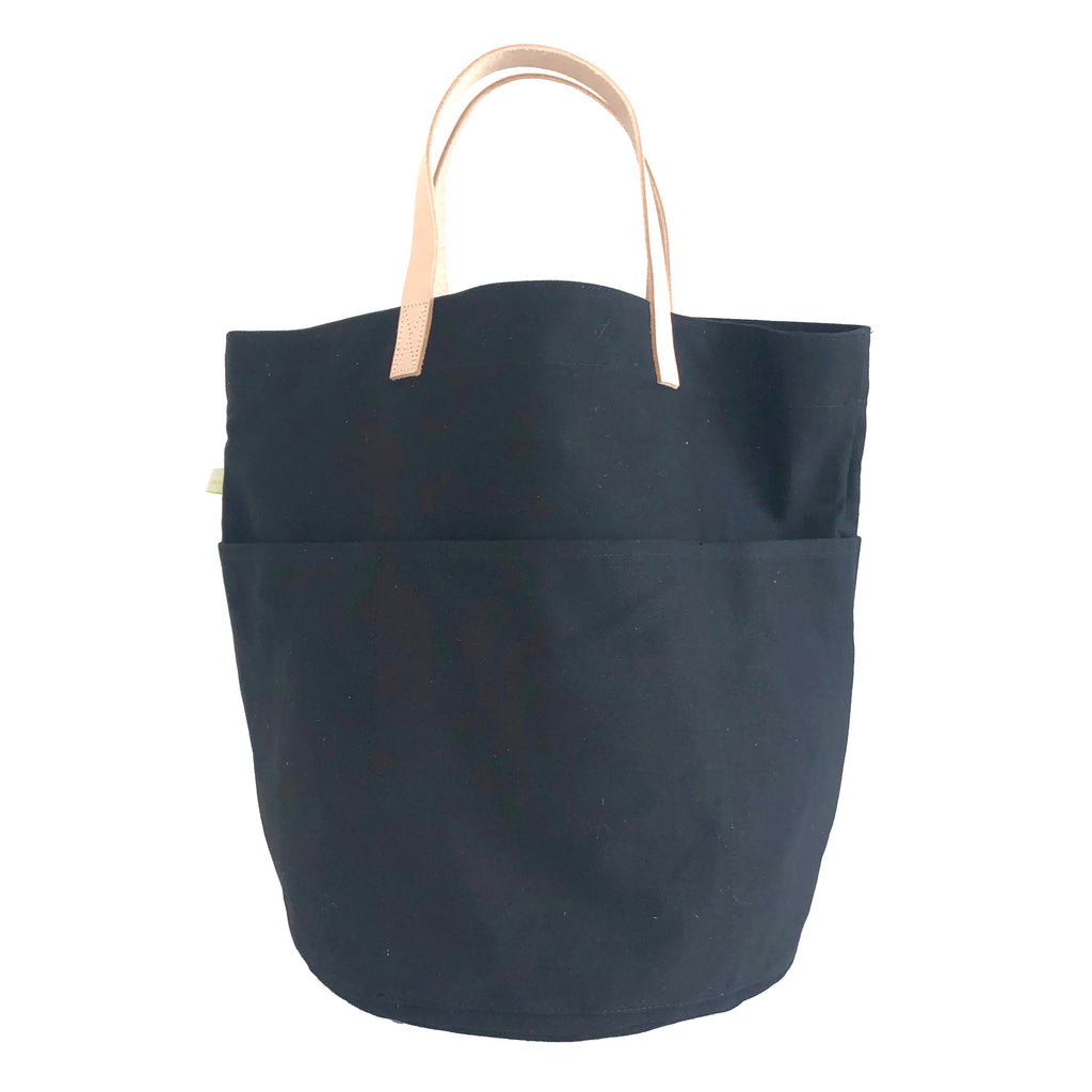 A Tall Circle Tote by See Design with leather handles.