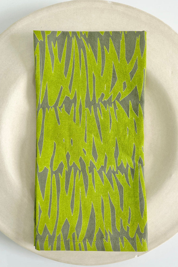 A vibrant lime green See Design napkins (Set of 4) on a white plate.