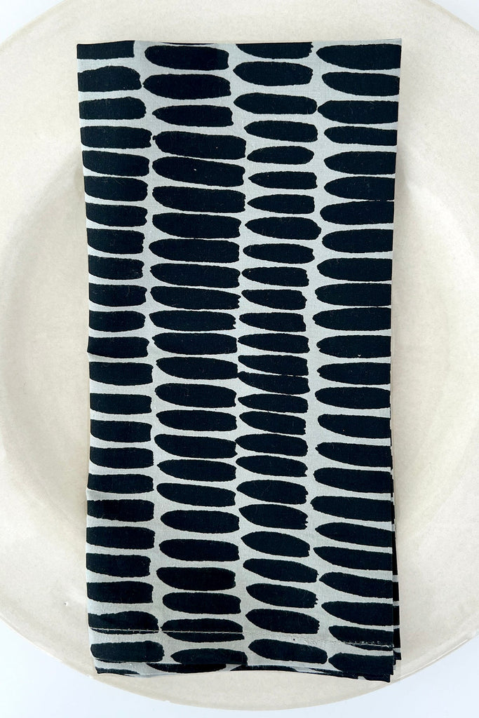 A See Design hand painted cotton napkin (Set of 4) on a plate.
