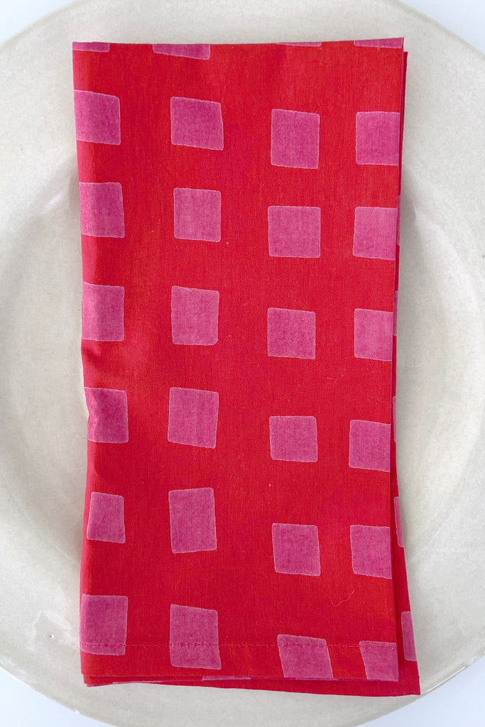 A vibrant red set of 4 napkins with pink squares, perfect for your dinner table from See Design.