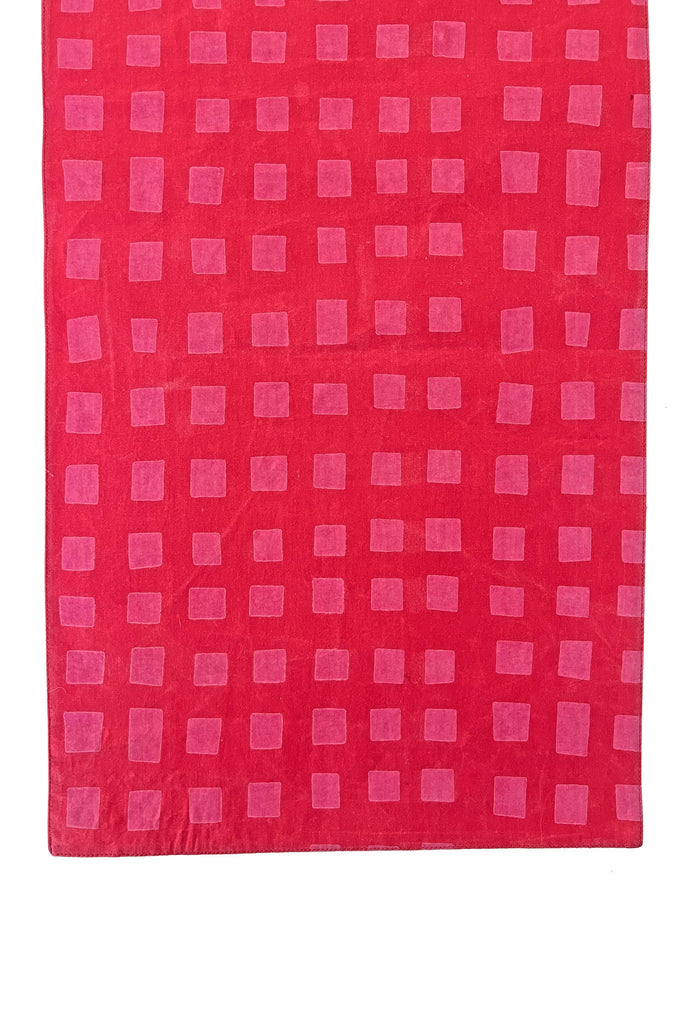 A red cotton Table Runner with pink squares and prints by See Design.