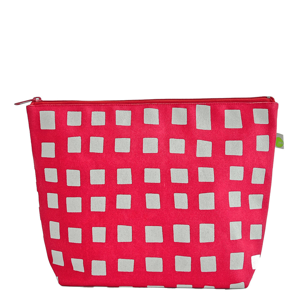 A pink See Design Travel Pouch Extra Large with white squares on it.