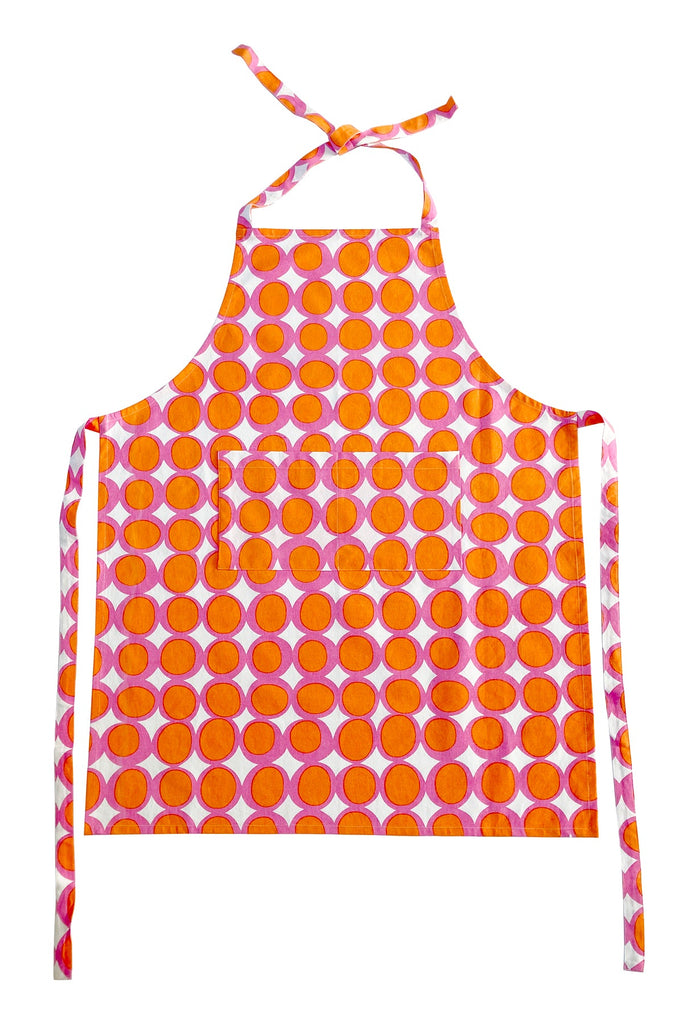 A pink and orange See Design kitchen apron with polka dots, perfect for cooking.