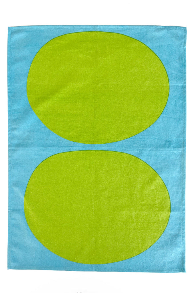 A vibrant See Design tea towel with hand painted designs in blue and green, featuring two ovals on it.